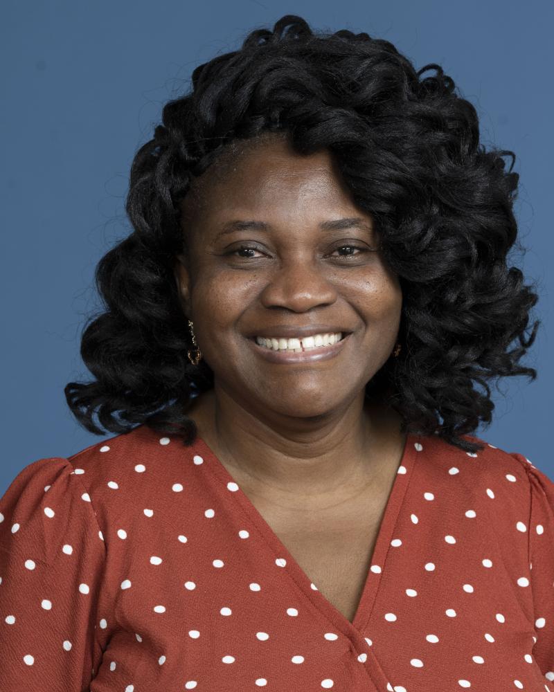 Woman with long curly hair and orange polka dot shirt 